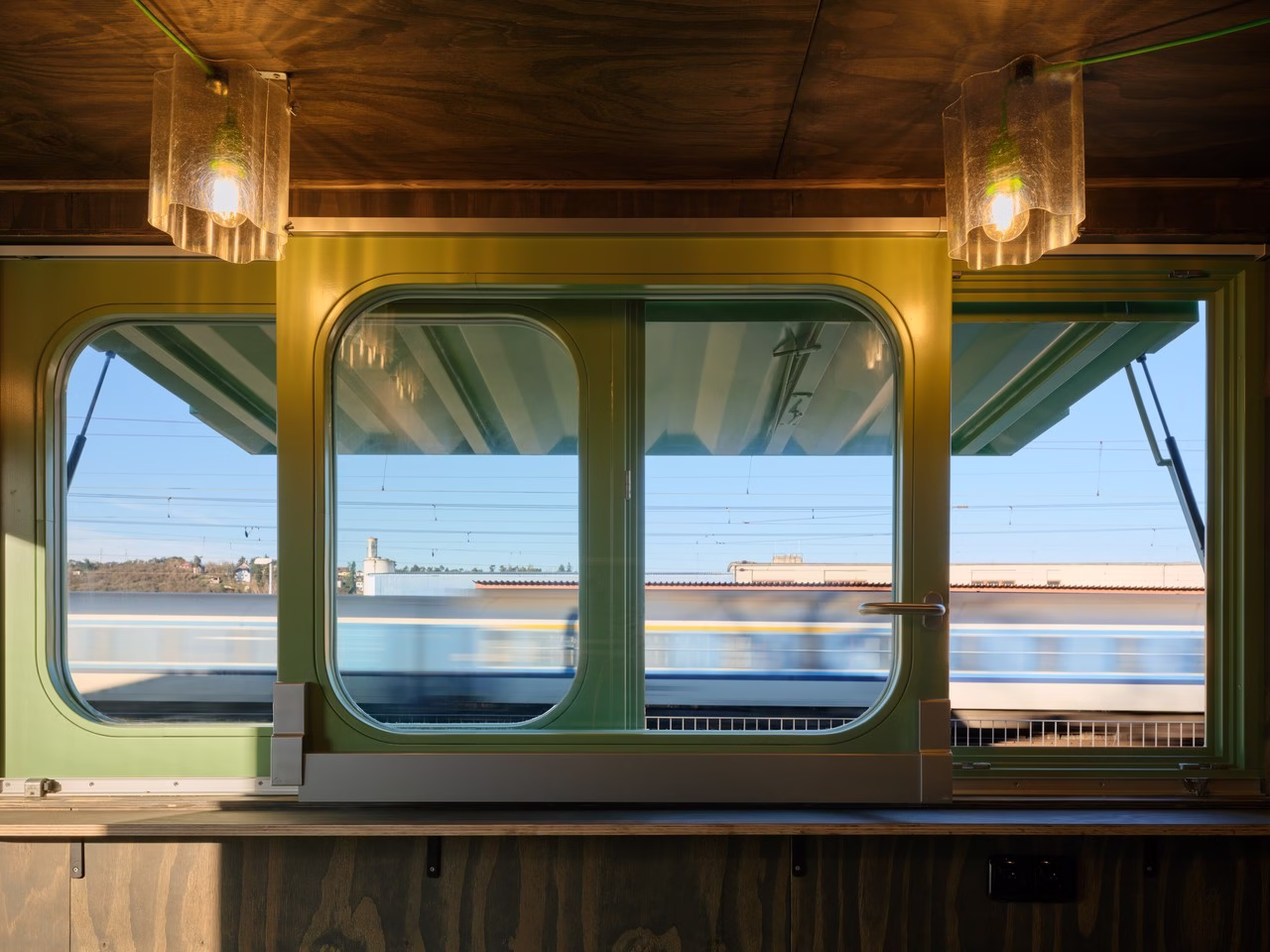 Zielona rama okienna, widok na przejeżdżający pociąg, nowoczesny design.