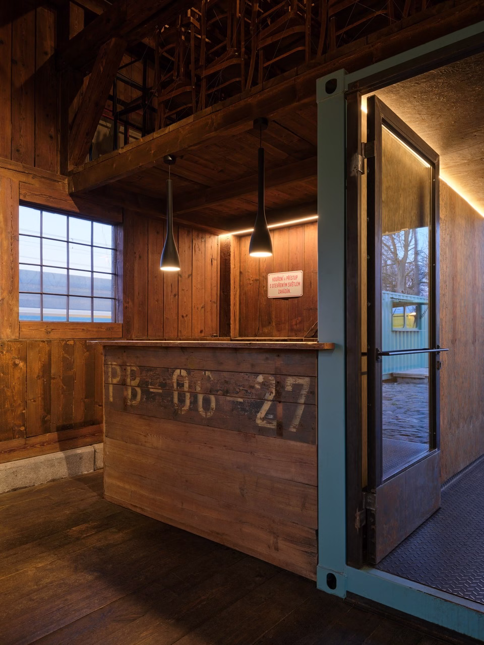 Rustykalny drewniany bar z nowoczesnymi lampami w industrialnym wnętrzu.