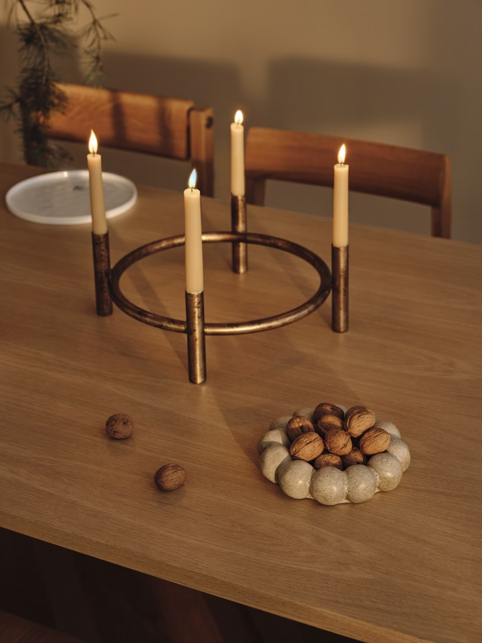 Świecznik z brązu i orzechy na drewnianym stole w jadalni.