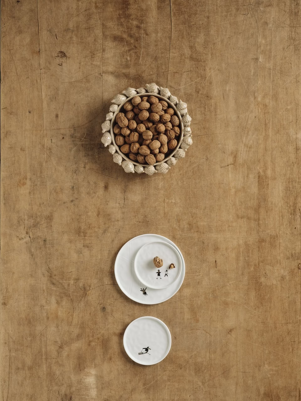 Dekoracyjna miska z orzechami na rustykalnym drewnianym stoliku.