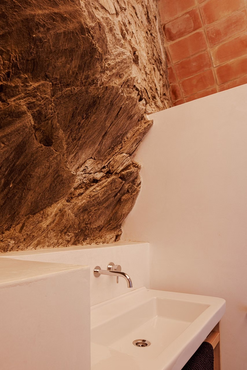Umywalka w łazience z naturalnym skalnym akcentem i biały tynk.